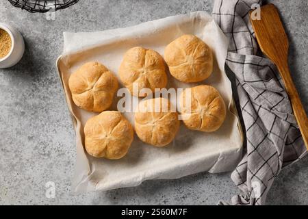 freshly baked bread buns on baking paper, top view Stock Photo