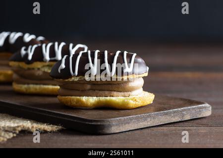 Eclairs with black chocolate and white chocolate with custard on rustic table. Traditional French dessert. Eclair Pastery concept Stock Photo