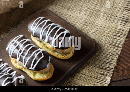 Eclairs with black chocolate and white chocolate with custard on rustic table. Traditional French dessert. Eclair Pastery concept Stock Photo