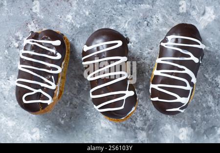Eclairs with black chocolate and white chocolate with custard on rustic table. Traditional French dessert. Eclair Pastery concept Stock Photo