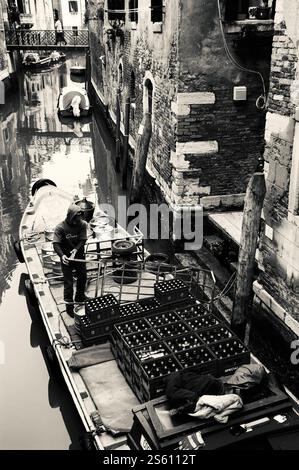 VENICE, ITALY - FEBRUARY 14, 2015: A man distributing beverages to the local pubs and restaurants unloads beer kegs and bottles from his boat and uplo Stock Photo