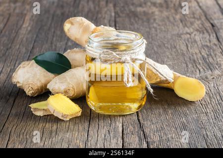 Glass bottle of essential ginger oil and ginger roots on wooden rustic background. Alternatine medicine. Zingiber officinale Stock Photo