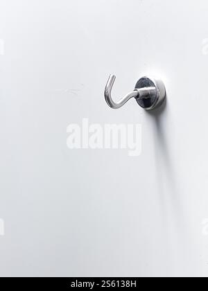 metal key on white wall, template for object, hanger on wall Stock Photo