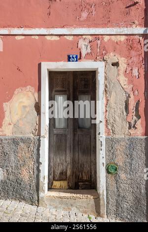 old wooden door in a weathered and cracked plaster wall Stock Photo