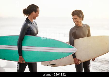 Surfing, sports and friends on the beach together during summer for training, fun or recreation. Surfboard, water or workout with a man and woman Stock Photo