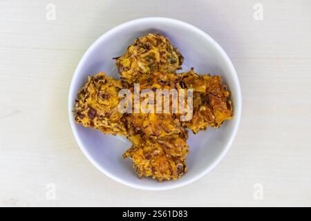 Crispy, crunchy pakora served on a white bowl. These delicious deep-fried fritters are a popular snack or appetizer in Bangladesh, India, and other pa Stock Photo