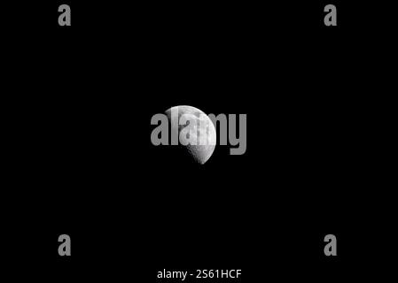 Waxing crescent moon glowing in the night sky, revealing its delicate curve against the darkness. Stock Photo
