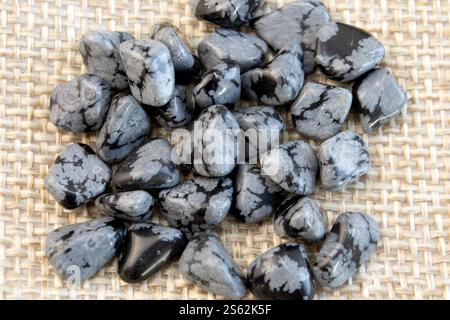 Tumbled close up snowflake obsidian on grey textured background top view Stock Photo