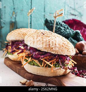 Veggie burger with pesto kale, hazelnuts, shredded carrot and red chicory on wooden board . Stock Photo
