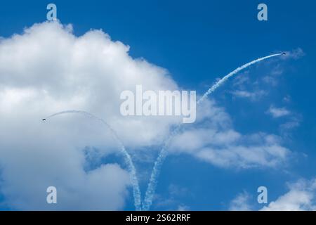 Exciting air stunts by two Aero L-29 Delfín jet planes in cloudy blue sky Stock Photo