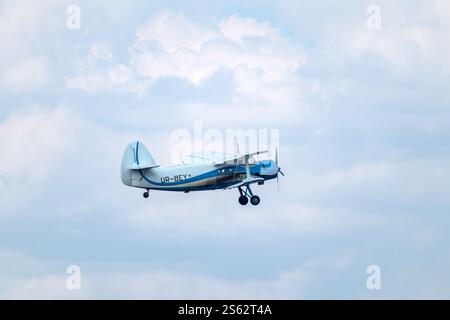 Antonov An-2 biplane passenger aircraft flying in blue sky with scenic clouds Stock Photo