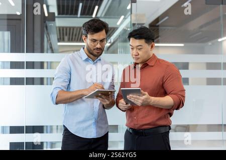 Diverse business colleagues in casual clothes at workplace, man writing data in notebook. Office workers team members at workplace inside office. Stock Photo