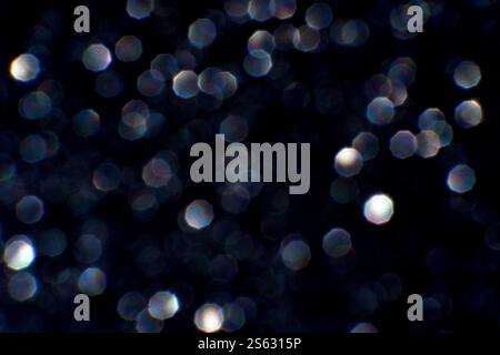 Sparkling bokeh lights on a dark background with hexagonal shapes and soft glow effects. Stock Photo