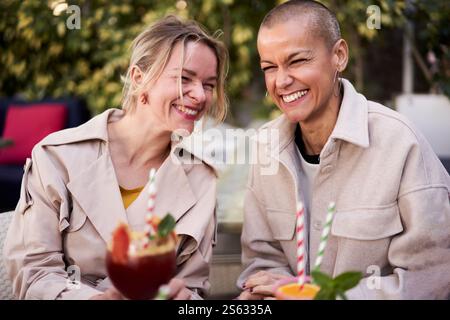Happy photo of three mature female friends having drinks outside. Stock Photo