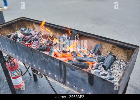 Fire and smoldering coals inside a metal grill for frying meat or vegetables outdoors. Preparing for a picnic Stock Photo