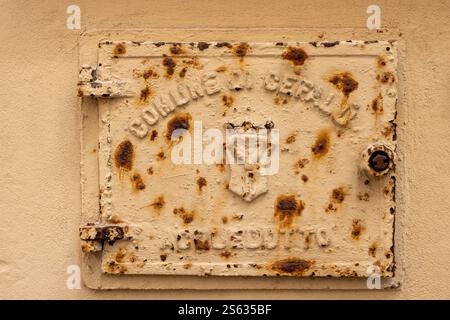 Comune of Cefalu Aquaduct (Comune di Cefalu Acquedotto). Old door on the wall of a house with yellow facade. Door partly rusted. Cefalu, Sicily, Italy Stock Photo