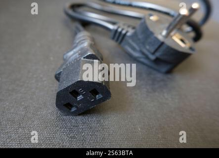 Power cable for informatics equipment. Black power cord on a black. Stock Photo