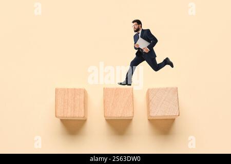 Running businessman with laptop and cubes on beige background. Concept of evolution Stock Photo