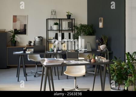 Workplaces of financial analysts with computers, lamps and stacks of financial paper documents on desks in spacious office Stock Photo