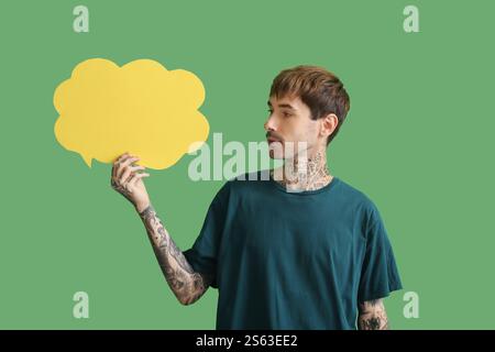 Happy young man with blank speech bubble on green background Stock Photo