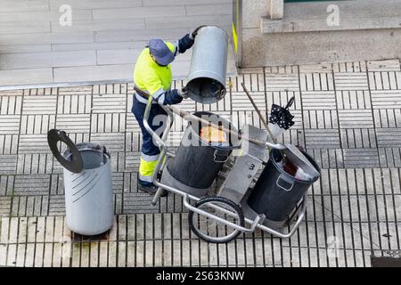 High angle view of a Cleaning worker emptying the trash into his cleaning cart on a city sidewalk Stock Photo