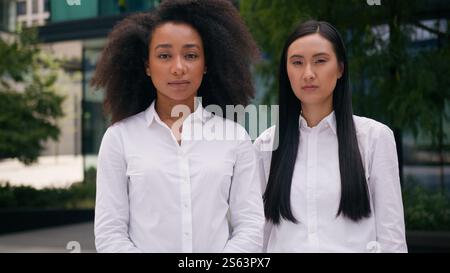 Successful confident African American Asian Korean Chinese women females colleagues coworkers businesswomen business standing posing looking at camera Stock Photo