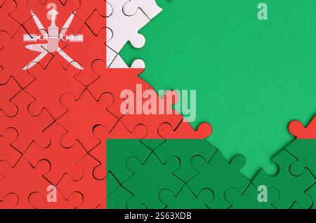 Oman flag is depicted on a completed jigsaw puzzle with free green copy space on the right side. Oman flag is depicted on a completed jigsaw puzzle Stock Photo