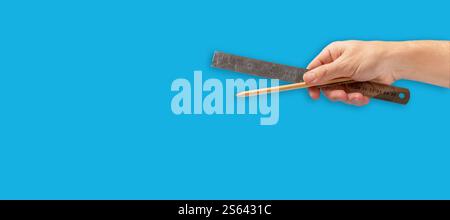 Ruler and pencil in hand on blue background Stock Photo