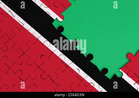 Trinidad and Tobago flag is depicted on a completed jigsaw puzzle with free green copy space on the right side. Trinidad and Tobago flag is depicted Stock Photo