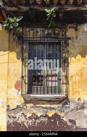 Antigua Guatemala, Sacatepequez, Guatemala. Peeling paint and a barred window on an old house. Stock Photo