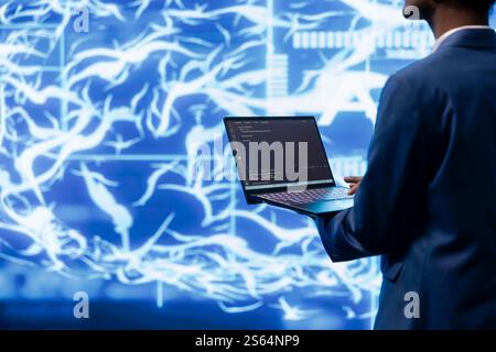 System administrator working on laptop, programming artificial intelligence computing simulating human brain. Man in workspace using notebook, building AI machine learning algorithms Stock Photo