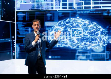 Company manager presenting how AI technologies can bring increased productivity in business sector during conference. Businessman using mic to discuss about about implementation of AI driven solutions Stock Photo