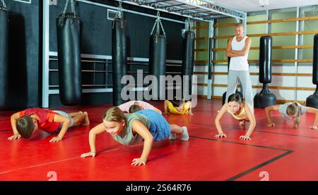 Children doing bench press exercises in gym Stock Photo