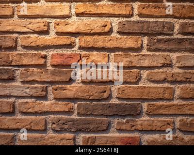 Close-up of a textured brick wall with warm tones, showing rough and uneven surfaces for design or construction use Stock Photo