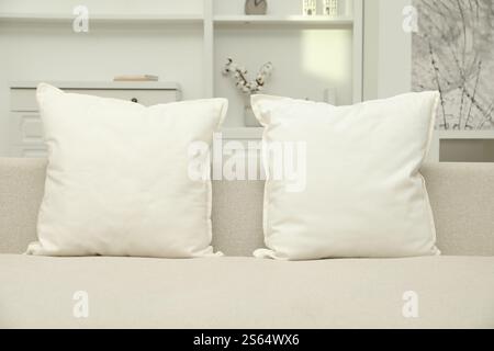 Blank soft pillows on cozy couch indoors Stock Photo