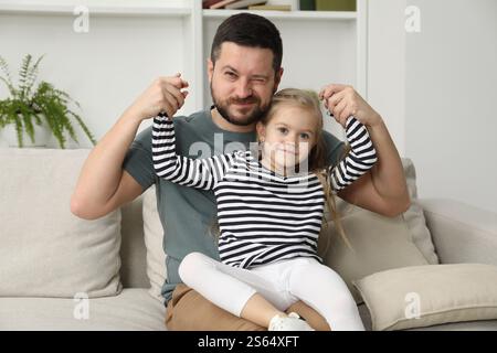 Father and his cute little daughter on sofa at home Stock Photo