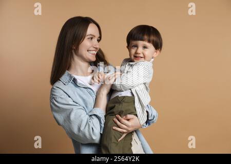 Family portrait of happy mother with her little son on beige background Stock Photo