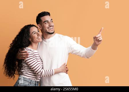 Nice Offer. Happy Young Arab Spouses Pointing Aside At Copy Space Stock Photo