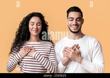 Thank You. Grateful Young Arab Man And Woman Keeping Hands On Chest Stock Photo