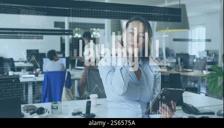 Analyzing data on tablet, businesswoman with graphs and charts image over office Stock Photo