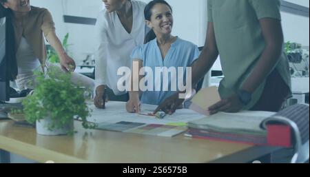 Image of diverse team collaborating on project in office Stock Photo