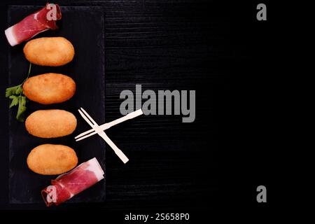 Croquettes with ham on rectangular slate plate with negative space on the right Stock Photo