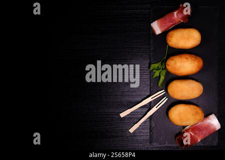 Croquettes with ham on rectangular slate plate with negative space on the left Stock Photo
