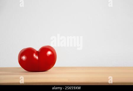 Heart shaped red tomato on empty cutting board with space for text or product placement. Stock Photo