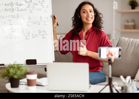 Lady teacher showing thumb up gesture, explaining math to students Stock Photo