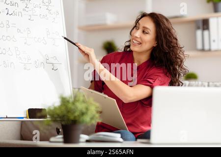 Lady teacher explaining math to students using pc Stock Photo