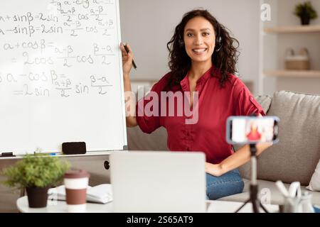 Lady teacher in headphones explaining trigonometric functions to students online Stock Photo