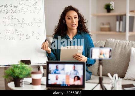 Lady teacher in headset explaining math to students online Stock Photo
