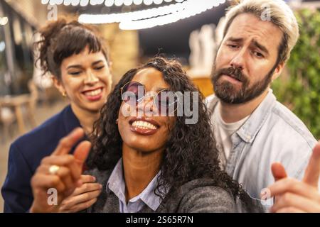 Close-up and personal point of view of multi-ethnic friends pulling funny faces while taking selfie in night party outdoors Stock Photo