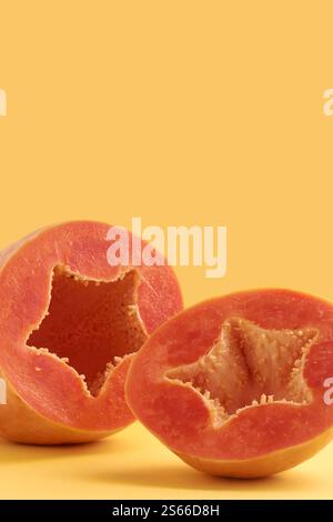 two halves of ripe papaya isolated yellow background, juicy sweet fruit with star shaped bright orange flesh ready to eat, side view with copy space Stock Photo
